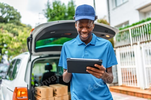 Preview: Cheerful delivery african man using tablet while working with van