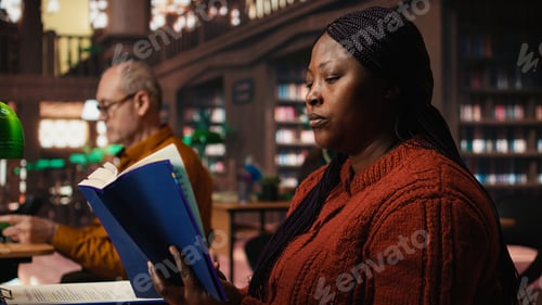 Preview: African american woman reading book and completing her class notes