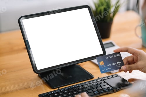 Preview: Close up of woman hands holding credit card and using laptop, tablet blank white screen.