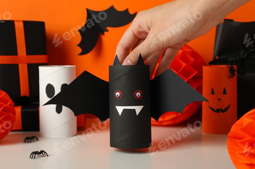 Preview: Gift boxes, paper halloween characters and hand on orange background