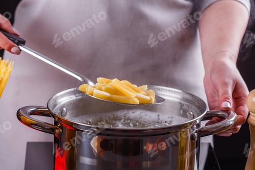 Preview: young woman in a gray apron is preparing pasta pesto