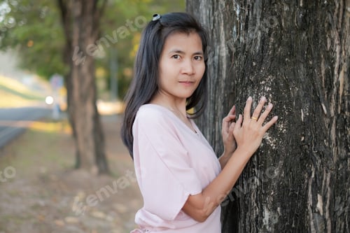 Preview: Portrait alone woman standing with big tree nature in park.