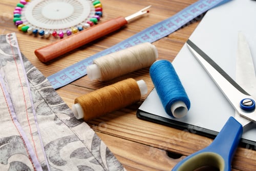 Preview: Colorful sewing supplies arranged around a blank clipboard on a wooden table