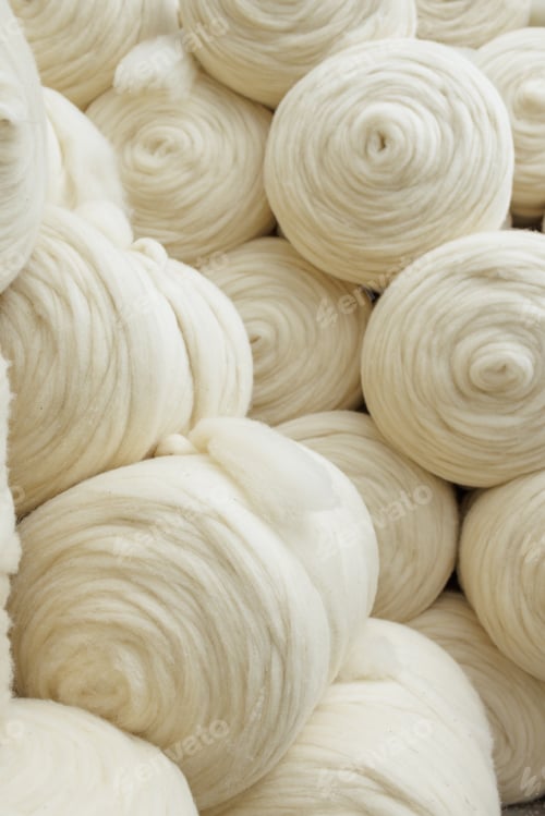 Preview: Carded wool fiber coils stacked in bulk for yarn spinning at a textile manufacturing plant.