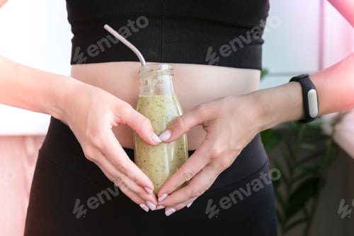 Visualização: Símbolo de mão no coração segurando smoothie bebida detox em forma e barriga magra mulher. Fitness bem-estar con