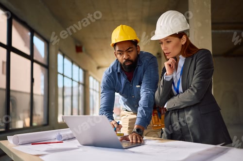 Preview: Black worker and female project manager working on laptop at construction site.