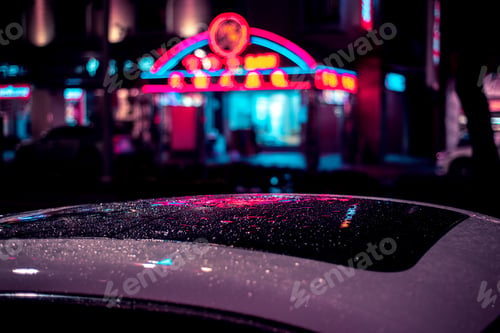Preview: Selective focus shot of a wet roof of a car in a city with a blurry building in the background