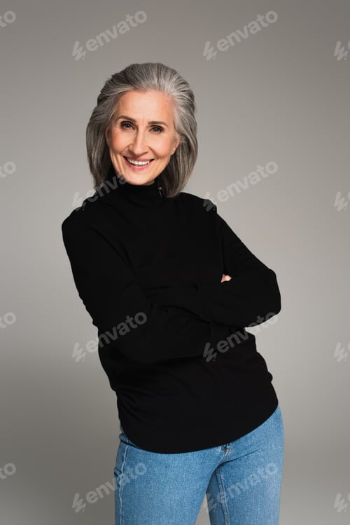 Preview: Smiling woman with crossed arms looking at camera isolated on grey