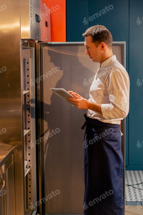 Preview: professional kitchen chef looks into the fridge and chooses ingredients for cooking food concept