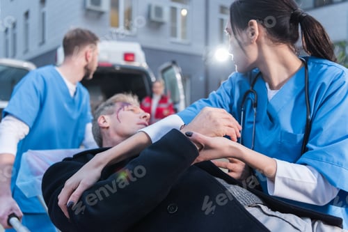 Preview: paramedics moving wounded mature man on ambulance stretcher