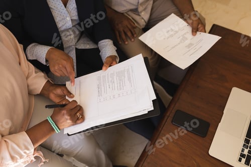 Preview: Senior woman signing property contract with real estate agent and senior man while sitting on a sofa