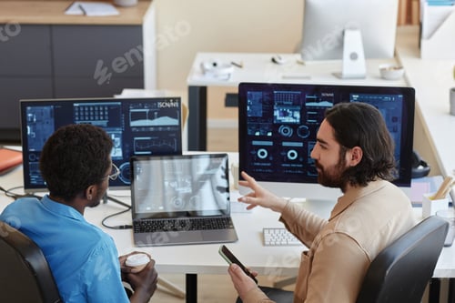 Preview: Young confident IT engineer explaining graphic data to his colleague