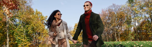 Preview: A joyful autumn stroll of a loving couple in cozy outfits amidst colorful fall foliage