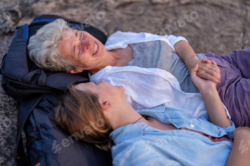 Preview: Backpack adventure hiking traveler mother and daughter laying on mountain talking smile looking face