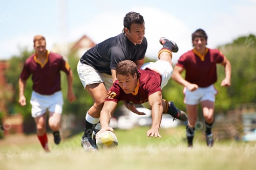 Preview: Full length shot of a young rugby player scoring a try mid tackle