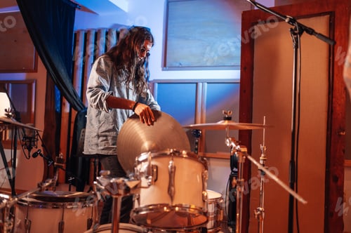 Preview: Skilled drummer putting cymbal on drums at music recording studio.