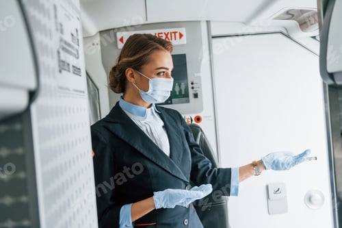 Preview: In protective gloves and mask. Young stewardess on the work in the passanger airplane