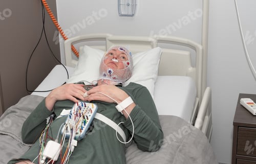 Preview: Middle aged woman measuring brain waves, examining polysomnography in sleep lab