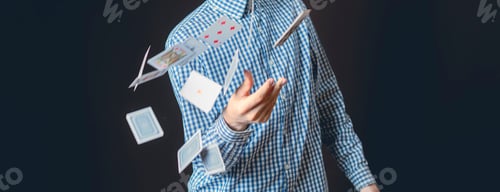 Preview: young male illusionist throw card on dark background isolated b