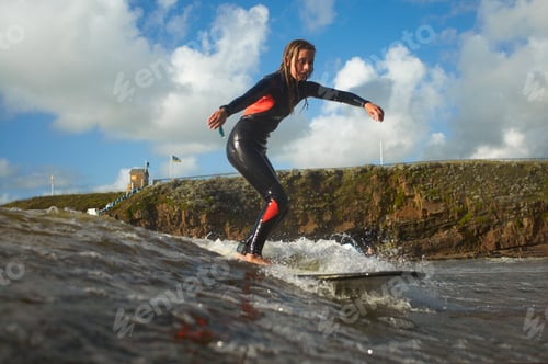 Preview: Young female surfer riding wave