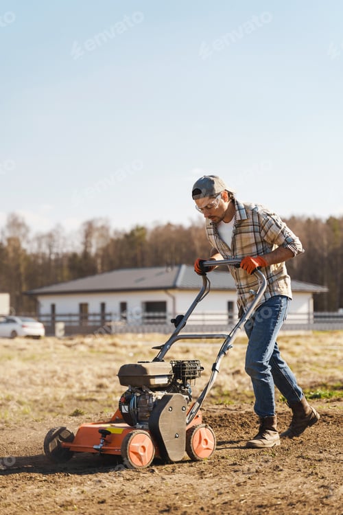 Preview: Man using aerator machine to scarification and aeration of lawn or meadow