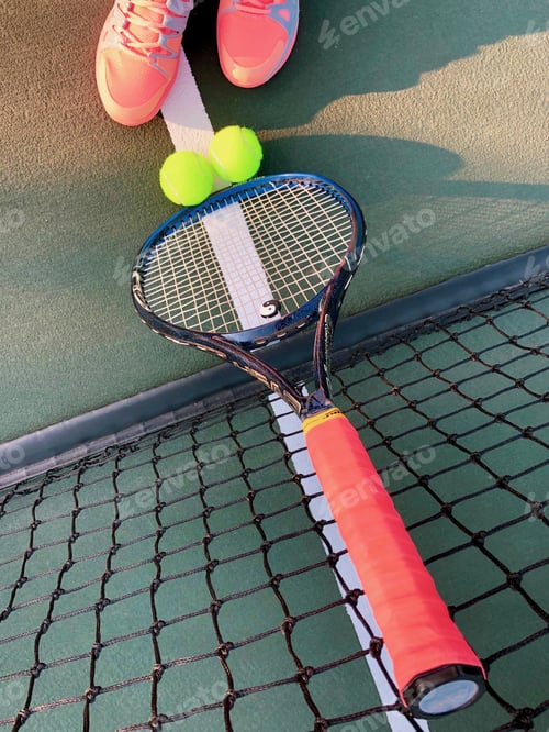 Preview: At the tennis court. Racket leaning against net with tennis balls and tennis shoes.