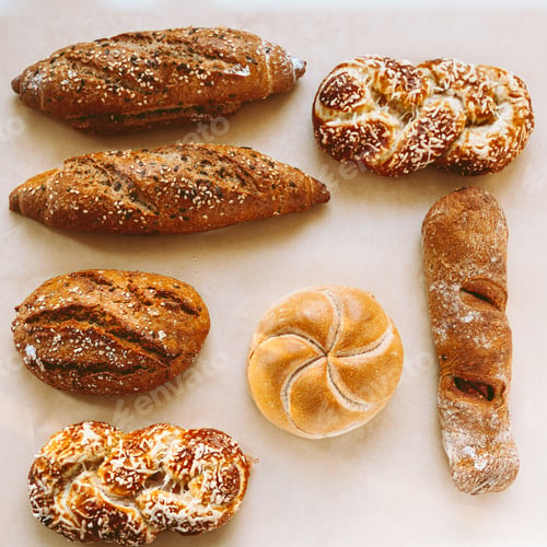 Preview: Assortment of baked bread on baking paper. Bakery background.