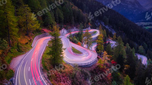 Preview: Maloja pass, Switzerland. A road with many curves among the forest. A blur of car lights.