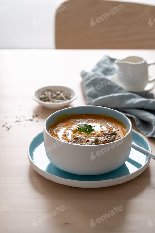 Preview: Pumpkin soup with coconut milk and seeds in blue bowl