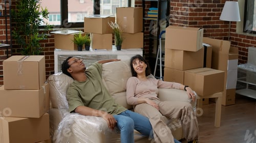 Preview: Tired husband and wife relaxing on couch after unpacking furniture