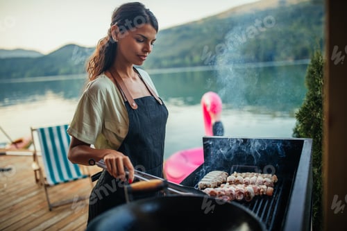 Preview: Lovely female grilling food at barbecue outdoors