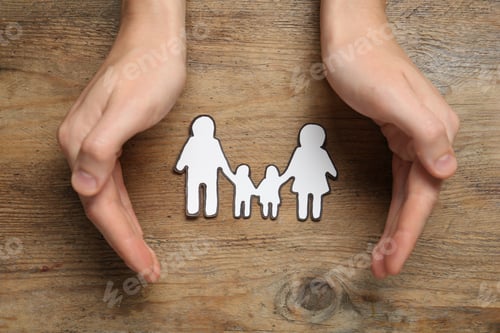 Preview: Woman with paper family cutout at wooden table, top view