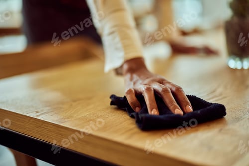 Preview: A black female waitress using a cloth, cleans the tables at the cafe.