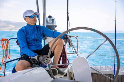 Preview: Young man captain stands at the helm and controls a sailboat during a journey by sea