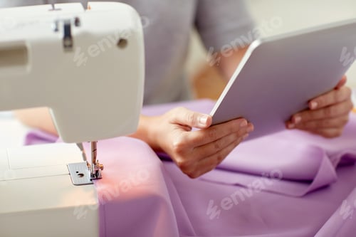 Preview: tailor with sewing machine, tablet pc and fabric