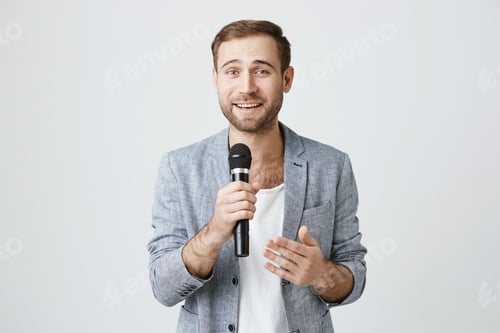Aperçu: Microphone, musique, chansons, concept de loisirs. Un beau chanteur caucasien regarde la caméra
