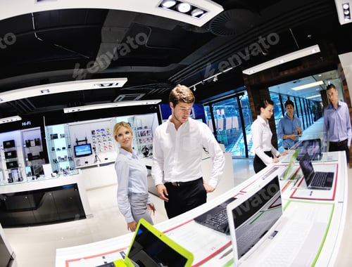 Preview: Young Couple In Consumer Electronics Store Looking At Latest Laptop, Television And Photo Camera
