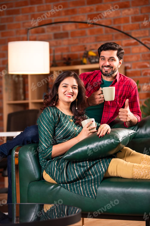 Preview: Indian young couple spending quality time while having tea or coffee at home