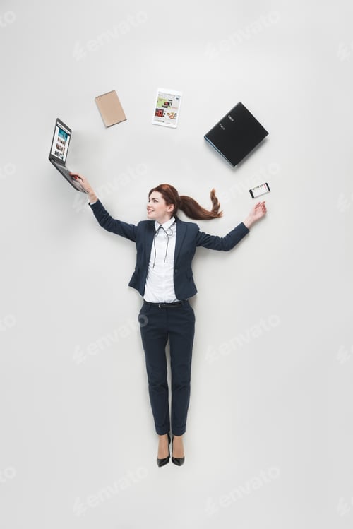 Preview: overhead view of businesswoman with various office supplies using laptop isolated on grey