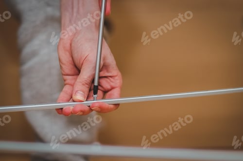 Preview: The hands of a caucasian young man are twisting a screw with a screwdriver connecting a metal part