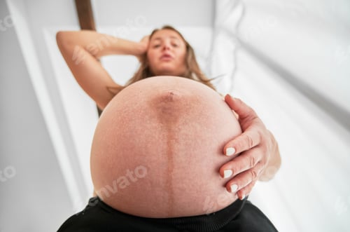 Preview: Low view of surprised pregnant woman with round tummy.