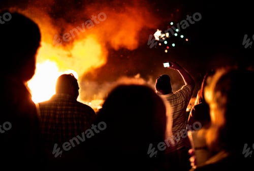Preview: Silhouettes of people around a large bonfire.