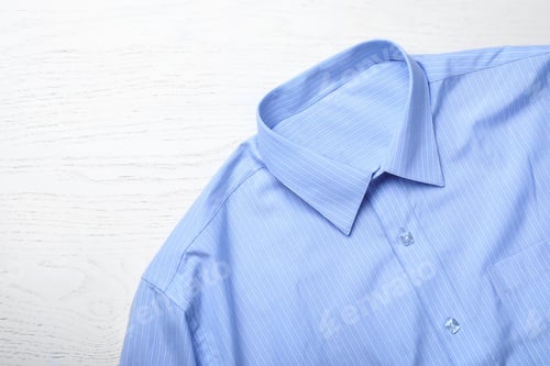 Preview: Stylish light blue shirt on white wooden table, top view. Dry-cleaning service