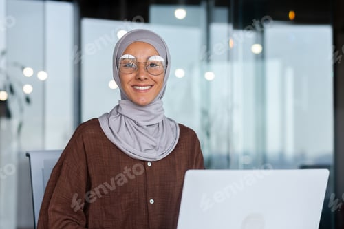 Preview: Portrait of successful businesswoman inside office with laptop, woman in hijab smiling and looking