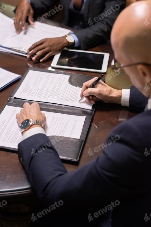 Preview: Mature businessman putting his signature on juridical document