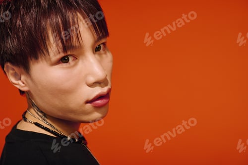 Preview: Handsome stylish young man poses against vibrant orange backdrop showcasing modern fashion