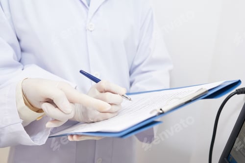 Medical Professional Writing On Clipboard In Hospital Setting