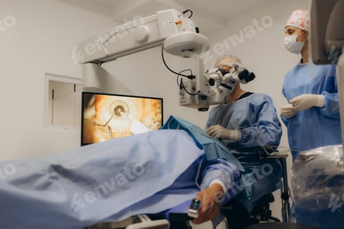 Preview: Male doctor doing surgery inside modern operating theater in surgical hospital.Microscope was use