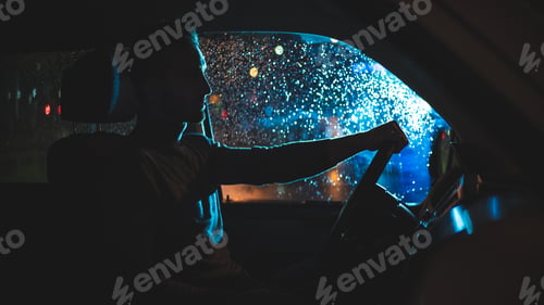 Preview: The handsome man is sitting in the car on the night rainy street.