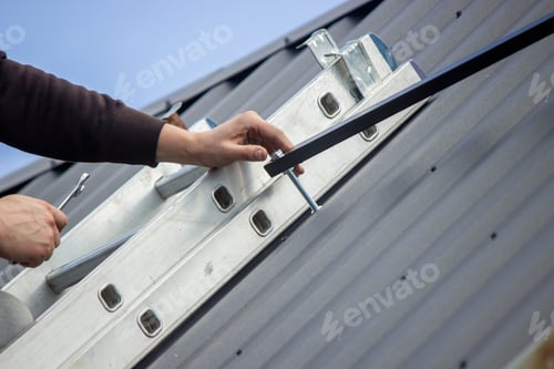Preview: A man is installing solar panel mounts on the roof. Selective focus